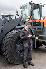 Poster - Serviceman with digital tablet on a background of the tractor.