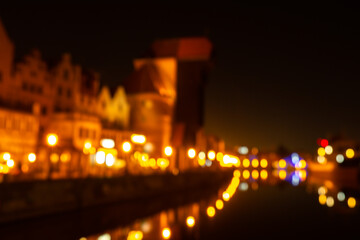 Wall Mural - Defocused photo of Old town in Gdansk at night for greeting card background. The riverside on Granary Island reflection in Moltawa River Cityscape at twilight. Ancient crane at dusk. Visit Gdansk