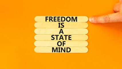 Freedom in mind symbol. Concept words Freedom is a state of mind on wooden sticks on a beautiful orange table orange background. Businessman hand. Business freedom is a state of mind concept.