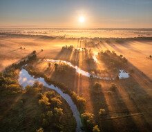 Aerial View Of Beautiful Curving River In Low Clouds At Sunrise In Autumn In Ukraine. Turns Of River, Meadows And Fields, Grass, Orange Trees, Golden Sun Rays At Dawn In Fall. Top View Of River Coast