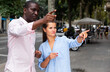 © JackF - Friendly African man helping young woman to find right address in city, pointing direction with hand
