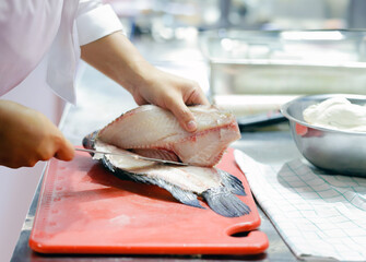 Wall Mural - Chef in a cuts up fish. Still life on the kitchen Board