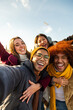 © Daniel - Selfie of multiracial happy friends enjoying winter day outdoors. Happy people looking at camera. Vertical. Copy space.