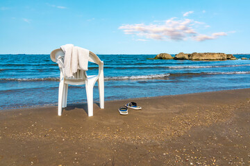 Poster - Coastal landscape with a lonely chair on a sandy beach. Summer vacation concept