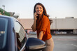 © Graphicroyalty - Successful woman standing outside and opening the car door. Businesswoman getting into the car while talking on the smartphone.