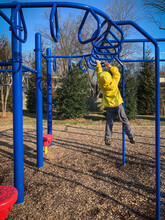 Young Boy Playing On Monkey Bars In Suburban Playground.
