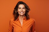 Fototapeta  - 40 - year - old woman wearing a bright clothes next to a orange background. Beautiful businesswoman, who is smiling and laughing at isolated background.