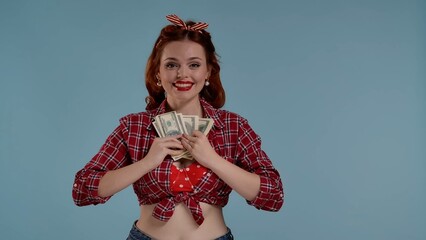 In the frame on a blue background young girl. She is holding money bills in her hands. She looks at the camera and presses them to herself. Apparently she has received her paycheck. She is happy HDR