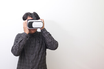 Portrait of Asian man in black plaid shirt using Virtual Reality (VR) glasses and looking up. Isolated image on white background