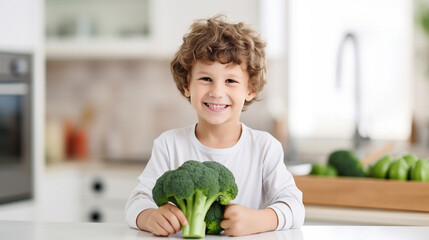 Little beautiful boy posing with broccoli in the kitchen. Healthy vegan baby foods concept.