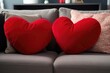 a pair of red love heart shaped cushions on a comfy sofa