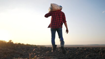 Sticker - farmer working with sack in agricultural field. agriculture a business farm concept. farmer worker carries a bag with harvest at sunset silhouette in lifestyle agricultural field