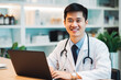 © VisualProduction - Asian doctor smiling while working on computer in his office, successful asian medical practitioner doing research on finding a cure
