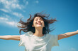A east Asian girl with arms wide open and huge smile on her face with eyes closed enjoying sunny day again a blue sky