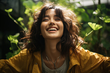 A beautiful 20 year old Japanese teen in yellow rain coat stands in a lush green garden with arms wide open beaming with pure happiness under sunshine brightly casting a warm glow on her face.