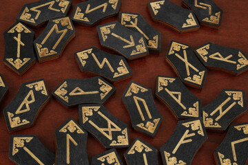 Wall Mural - Many black wooden runes on wooden table as background.