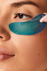 crop unrecognizable woman with under eyes patch in light