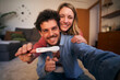 Selfie mobile smiling young adult Caucasian couple looking joyful at camera and holding positive pregnancy test. Focus hands predictor. People in love expecting baby. Future happy millennial family. 