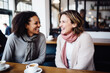 © Jasmina - Happy smiling middle aged female friends sitting in a café laughing and talking during a lunch break