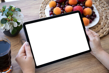 female hands holding computer tablet with isolated screen on table background of fruits in cafe