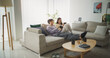 © Kitreel - South Korean Couple Sitting on a Cozy Couch, Playing Funny Arcade Video Games Together in a Stylish Bright Living Room. Beautiful Couple in a Relationship Enjoying Time on a Sofa at Home