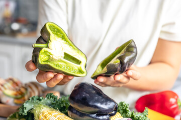 Wall Mural - Cut black bell pepper green inside in female hands.