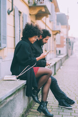 Young multiethnic couple hugging using smartphone toghether outdoors at night