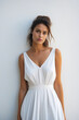 © VISUAL BACKGROUND - Woman in white dress posing for picture with her hands on her hips.