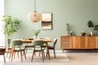 Wooden dining table and chairs against green wall. Scandinavian, mid-century home interior design of modern dining room.