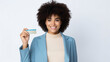 Portrait of happy young woman with afro hair showing credit card while standing on white background