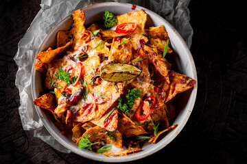 plate of delicious tortilla nachos with melted cheese sauce, ground beef, jalapeno peppers in bowl