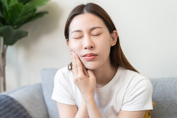 Wall Mural - Closing eyes asian young woman hand touching cheek, face expression from toothache, tooth decay or sensitivity, Having tooth or teeth problem or inflammation, suffering from health. Sensitive teeth.