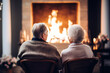 an elderly couple is sitting in front of a burning fireplace fireplace, and have a nice conversation
