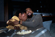 © lordn - African American couple watching a movie at home over a streaming cable service. Movie night. A woman is very emotional