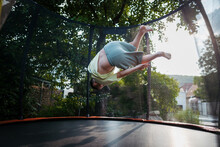 Little Girl Jumping On Trampoline On Backyard.