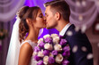 Wedding couple kissing and hugging in the room decorated with flowers in purple colors.
