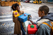 © Marko Geber - Young mixed lesbian couple taking pictures on a smartphone of presents they bought while walking in the city