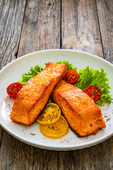 Wall Mural - Seared salmon steaks with lettuce and lemons on wooden table
