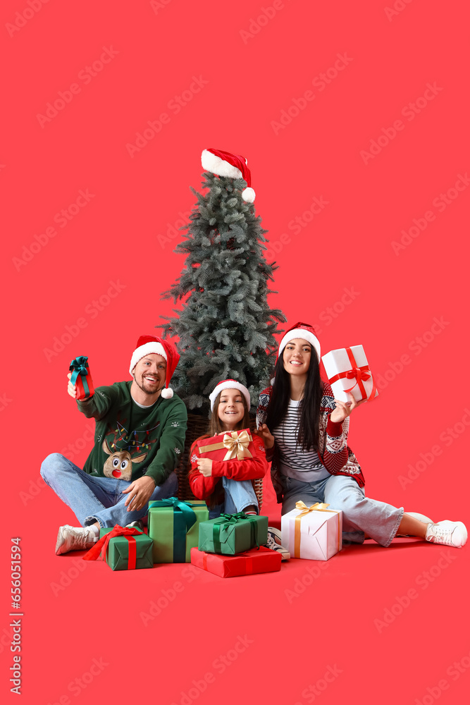 Happy family with presents and Christmas tree on red background