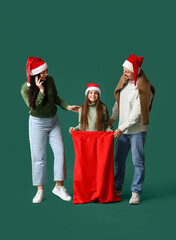 Poster - Happy family with bag of Christmas gifts on green background