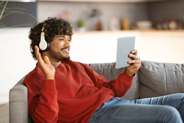 Wall Mural - Cheerful Indian Man Having Video Call On Digital Tablet At Home