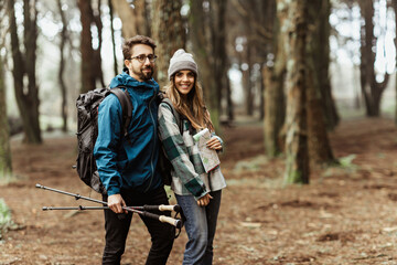 Wall Mural - Happy young caucasian family in jackets with backpack, map hugging, enjoy free time at weekend, walk in cold forest