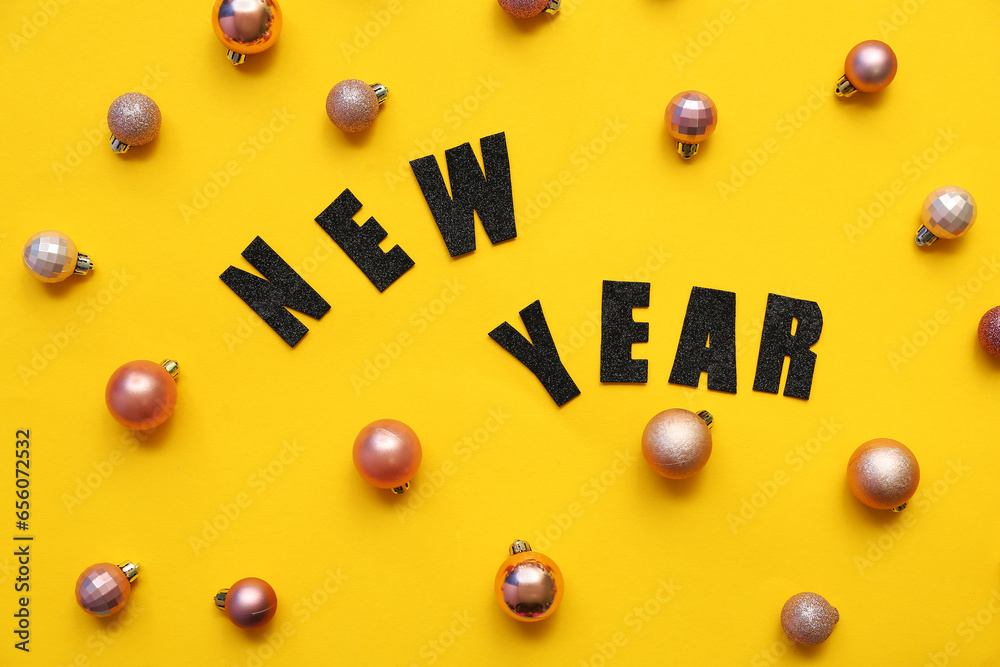 Text NEW YEAR with Christmas balls on yellow background