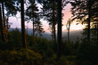 View from black coniferous forest on hills. Colorful sunset during spring in Jeseniky, Czech republic