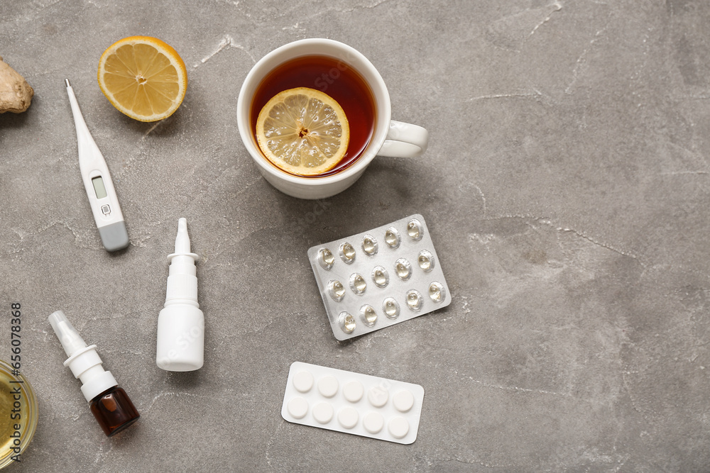 Nasal drops with thermometer, lemon tea and pills on grunge background