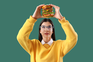 Poster - Young woman with big sandwich on green background