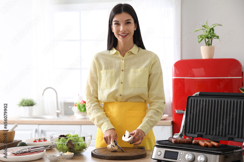 Young woman cutting mushroom in kitchen