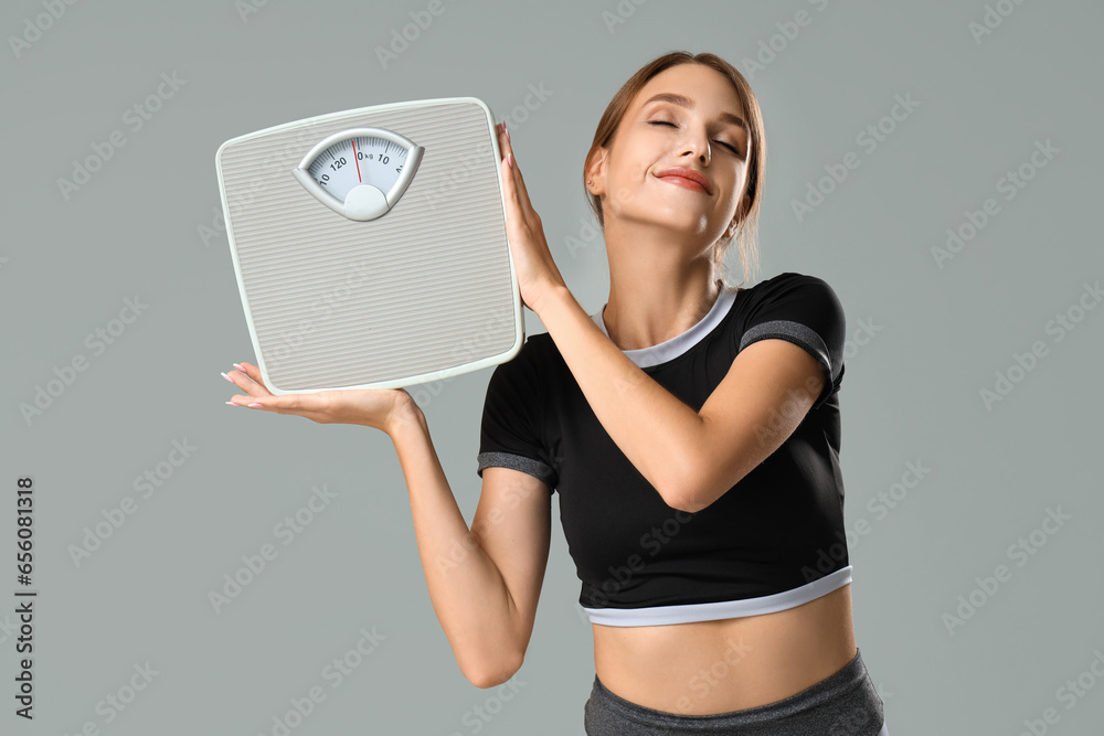 Beautiful young woman with scales on grey background. Weight loss concept