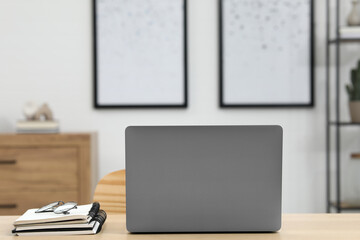 Sticker - Home workspace. Laptop, glasses and stationery on wooden desk in room