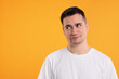 Portrait of embarrassed young man on orange background, space for text